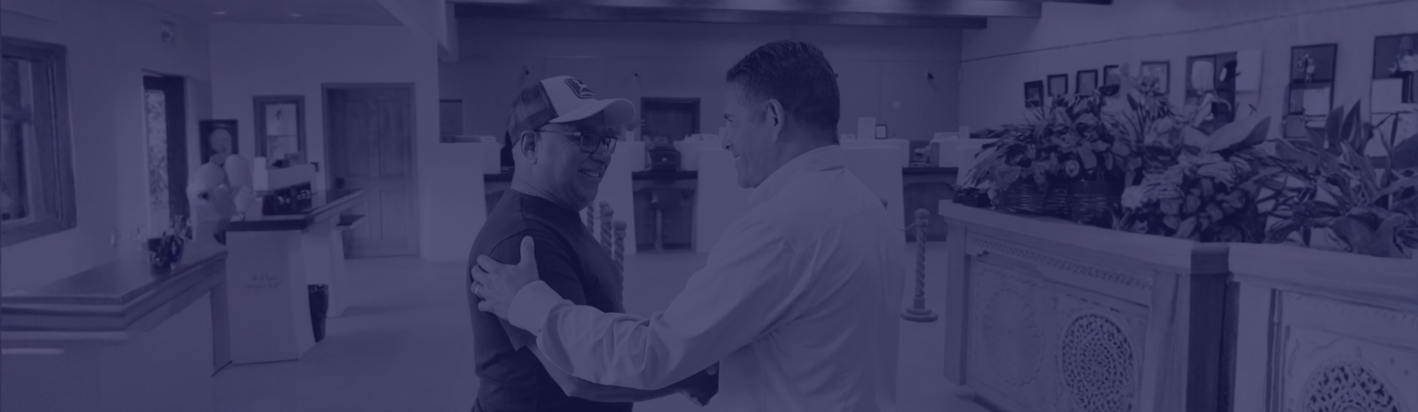 Angel Reyes shaking hands with Michael Silva in the main office lobby.