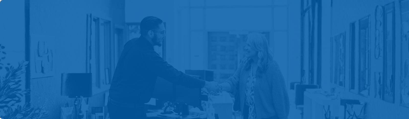 Jerome Vigil loan coordinator shaking hands with a female customer in loan lobby.